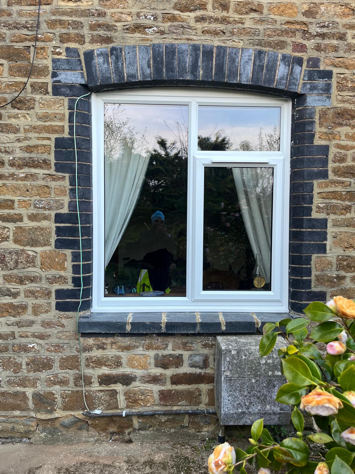 White uPVC casement window installed in stone cottage with arched brick header